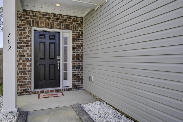 view of exterior entry featuring brick siding