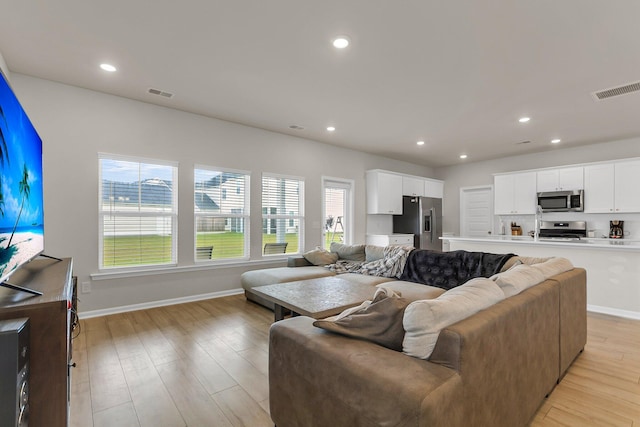 living room featuring recessed lighting, visible vents, and light wood-style floors