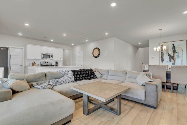 living room with an inviting chandelier, recessed lighting, and light wood-type flooring