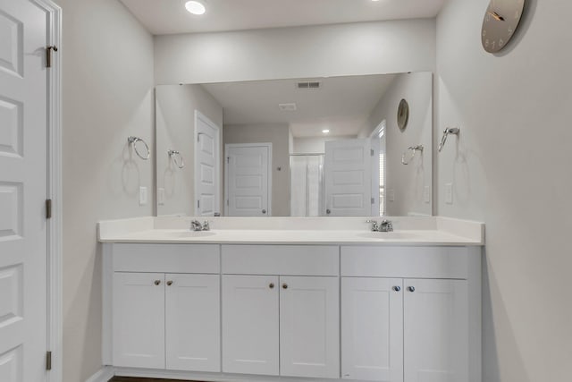 bathroom featuring double vanity, visible vents, a shower stall, and a sink