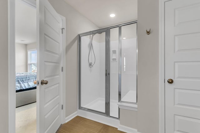 full bath featuring ensuite bath, wood finished floors, a stall shower, and baseboards