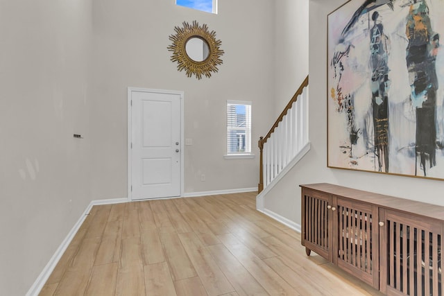 foyer with stairway, a high ceiling, baseboards, and wood finished floors