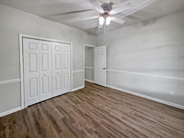 unfurnished bedroom with ceiling fan, a textured ceiling, a closet, and dark hardwood / wood-style flooring