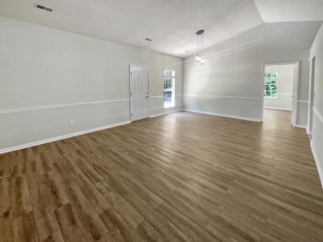 unfurnished room featuring lofted ceiling, dark hardwood / wood-style flooring, and a textured ceiling