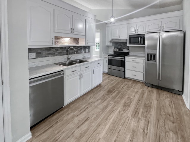 kitchen with lofted ceiling, sink, stainless steel appliances, and white cabinetry