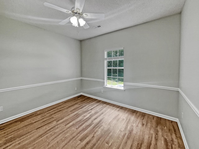 empty room with a textured ceiling, ceiling fan, and hardwood / wood-style floors