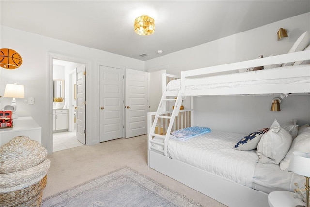 bedroom featuring light carpet and connected bathroom