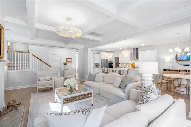 living room featuring an inviting chandelier, coffered ceiling, ornamental molding, beamed ceiling, and light wood-type flooring