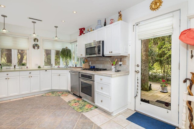 kitchen featuring stainless steel appliances, plenty of natural light, recessed lighting, backsplash, and white cabinets