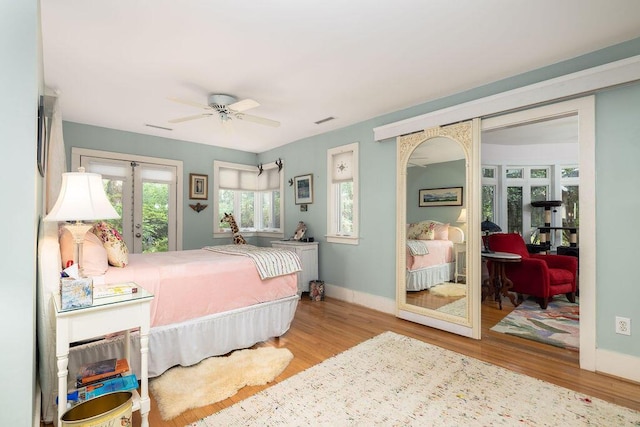 bedroom featuring french doors, wood finished floors, baseboards, and a ceiling fan