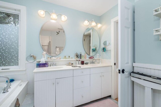 full bath with double vanity, tiled tub, and tile patterned floors