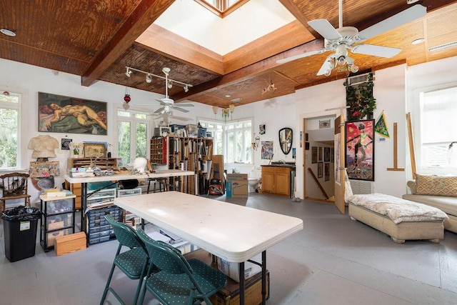 dining space with a ceiling fan, beamed ceiling, wood ceiling, and concrete flooring