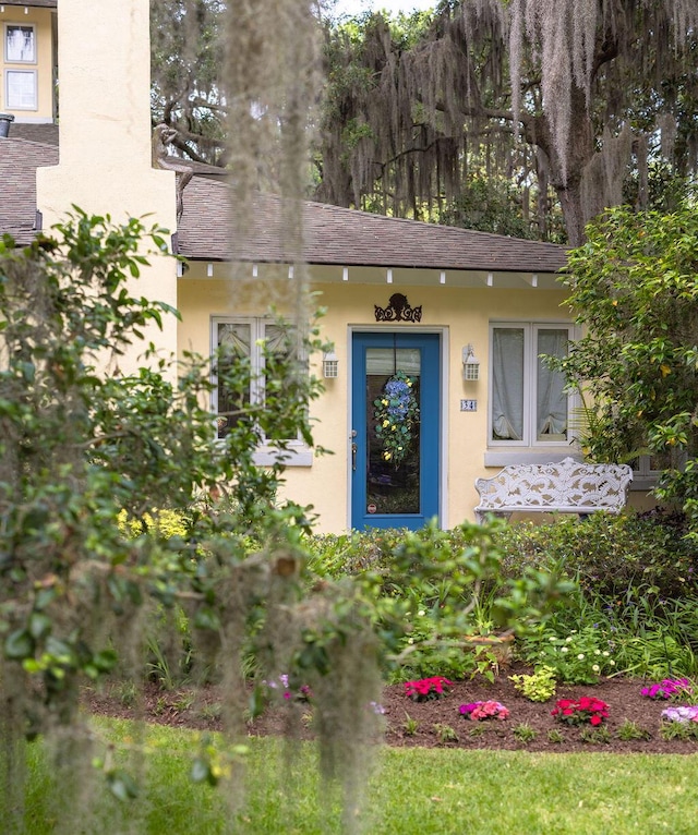 property entrance featuring stucco siding and roof with shingles