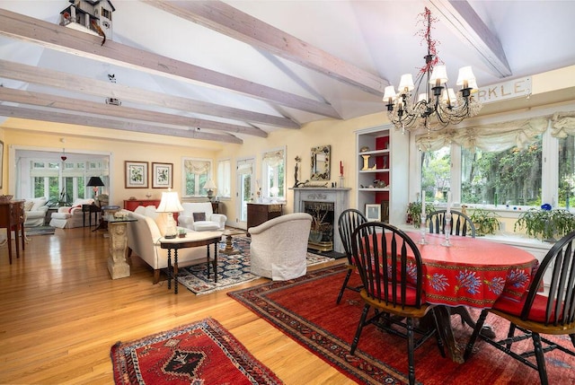 dining area featuring a chandelier, beam ceiling, a fireplace, and wood finished floors