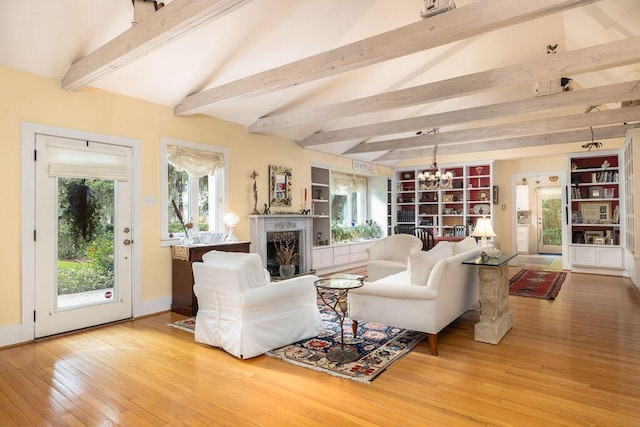 living area with wood-type flooring, a fireplace, a chandelier, beamed ceiling, and baseboards