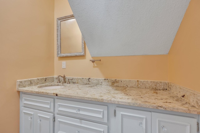 bathroom with vanity, vaulted ceiling, and a textured ceiling