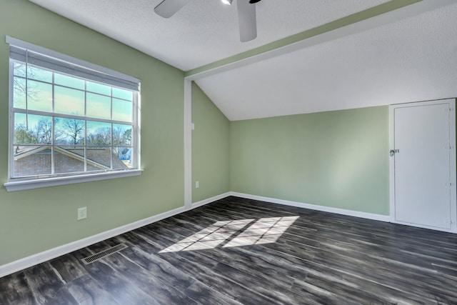 additional living space featuring lofted ceiling, ceiling fan, dark wood-type flooring, and a textured ceiling