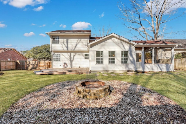 back of house featuring a fire pit, a lawn, a sunroom, and a deck