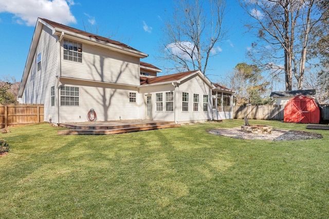 back of house featuring a storage shed, a lawn, a deck, and a fire pit