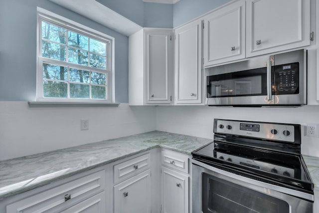 kitchen featuring light stone countertops, white cabinetry, and appliances with stainless steel finishes