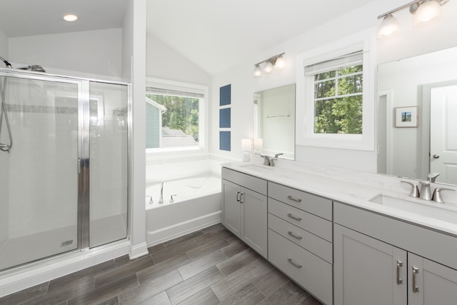 bathroom featuring vanity, independent shower and bath, and lofted ceiling