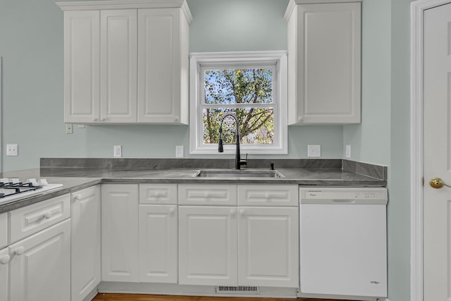 kitchen featuring white appliances, a sink, white cabinets, and dark countertops