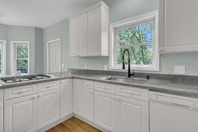 kitchen with white appliances, a sink, plenty of natural light, and white cabinetry