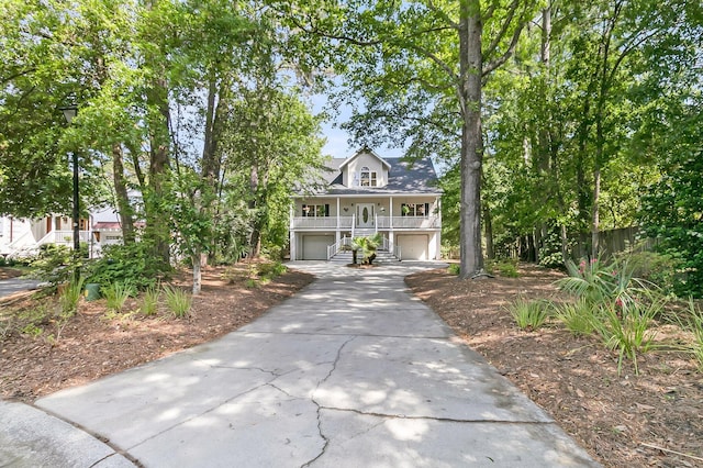 coastal home with a garage, driveway, covered porch, and stairs