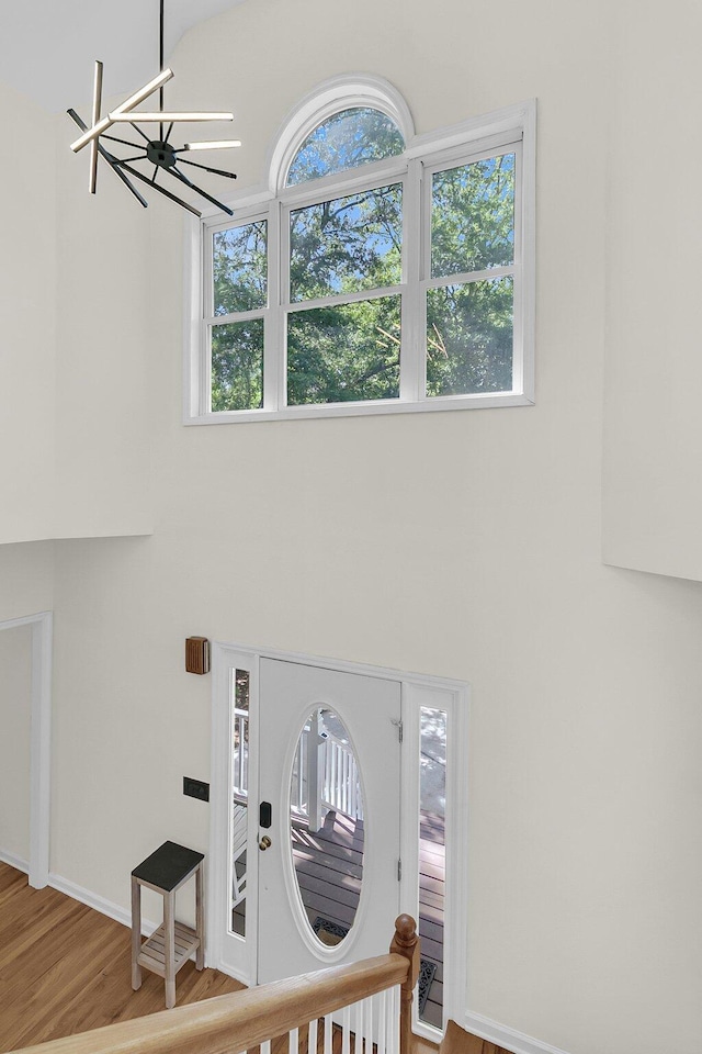 foyer entrance with a chandelier, wood finished floors, a towering ceiling, and baseboards