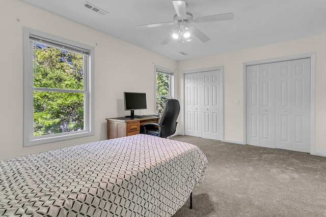 carpeted bedroom featuring multiple closets, an office area, ceiling fan, and baseboards