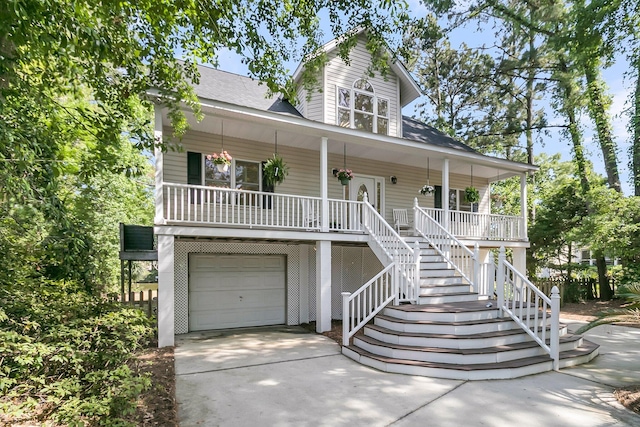 coastal inspired home featuring covered porch, a garage, concrete driveway, stairway, and roof with shingles