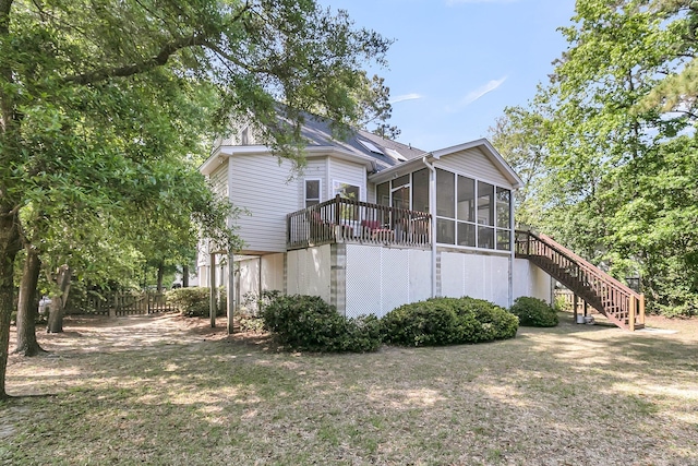 view of property exterior featuring a sunroom, stairway, and fence