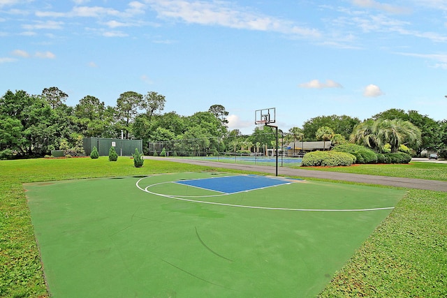 view of sport court featuring a tennis court, community basketball court, and view of wooded area