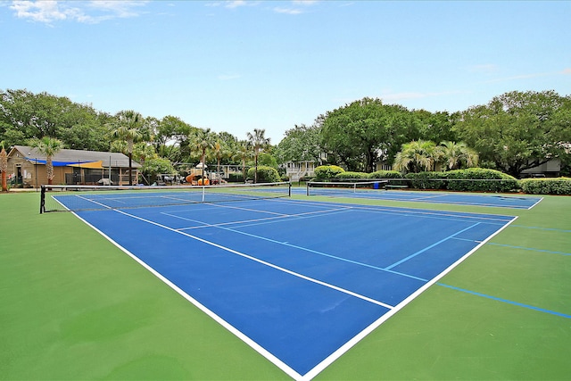 view of tennis court featuring community basketball court, fence, and view of scattered trees