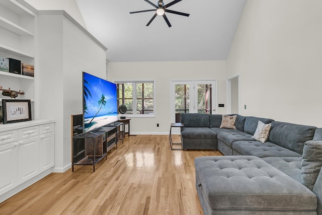 living room featuring high vaulted ceiling, a ceiling fan, baseboards, and light wood-type flooring
