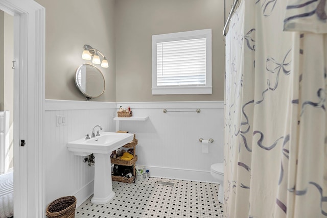 68 Vanderhorst St Unit A, Charleston, SC 29403 - bathroom with a wainscoted wall and a shower with shower curtain