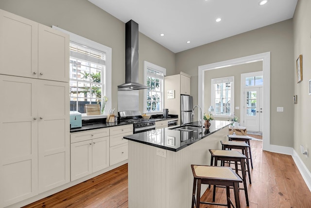 68 Vanderhorst St Unit A, Charleston, SC 29403 - kitchen with stainless steel appliances, wall chimney exhaust hood, a kitchen breakfast bar, light wood-style floors, and an island with sink