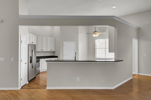 kitchen featuring appliances with stainless steel finishes, white cabinetry, wood-type flooring, ceiling fan, and kitchen peninsula