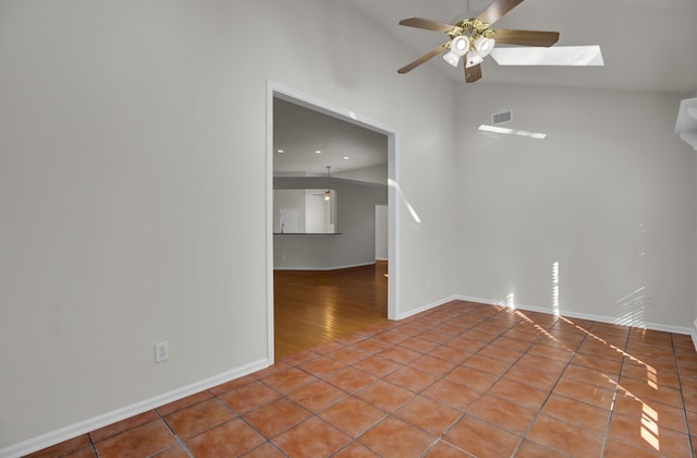 unfurnished room featuring light tile patterned floors, lofted ceiling with skylight, and ceiling fan