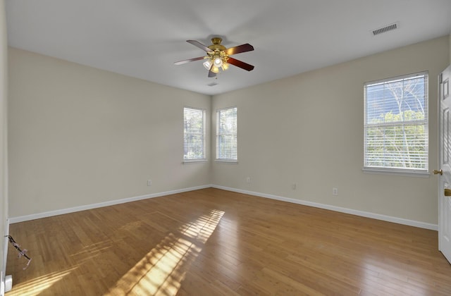 empty room featuring ceiling fan, a healthy amount of sunlight, and light wood-type flooring