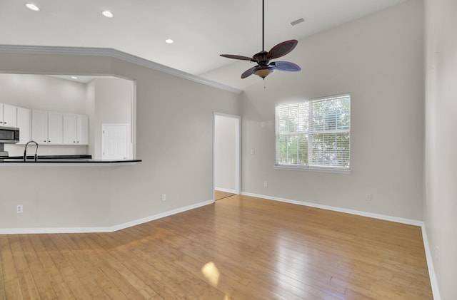 unfurnished living room with crown molding, ceiling fan, high vaulted ceiling, and light hardwood / wood-style floors