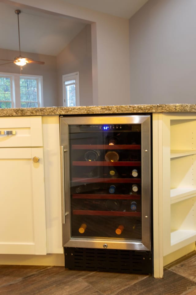 interior space with white cabinets, light stone counters, beverage cooler, and dark wood-style flooring