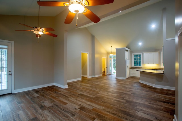 unfurnished living room featuring baseboards, dark wood-type flooring, a healthy amount of sunlight, and high vaulted ceiling