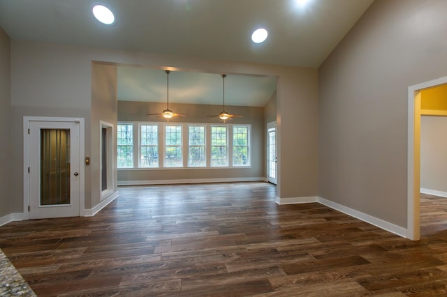 unfurnished living room with high vaulted ceiling, dark wood-type flooring, and baseboards