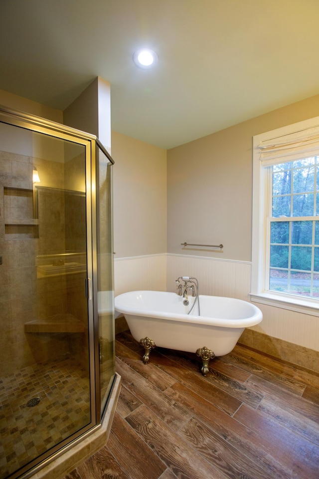 bathroom featuring wainscoting, a freestanding bath, a shower stall, and wood finished floors