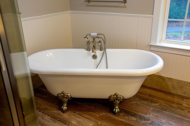 bathroom featuring a wainscoted wall and a freestanding tub