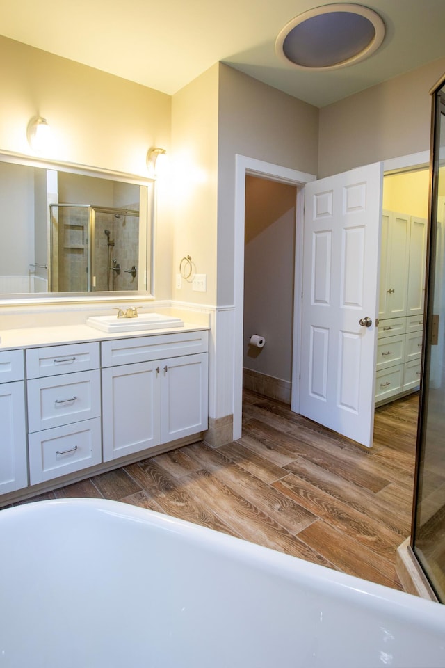 full bath featuring double vanity, wood finished floors, a shower stall, and a sink