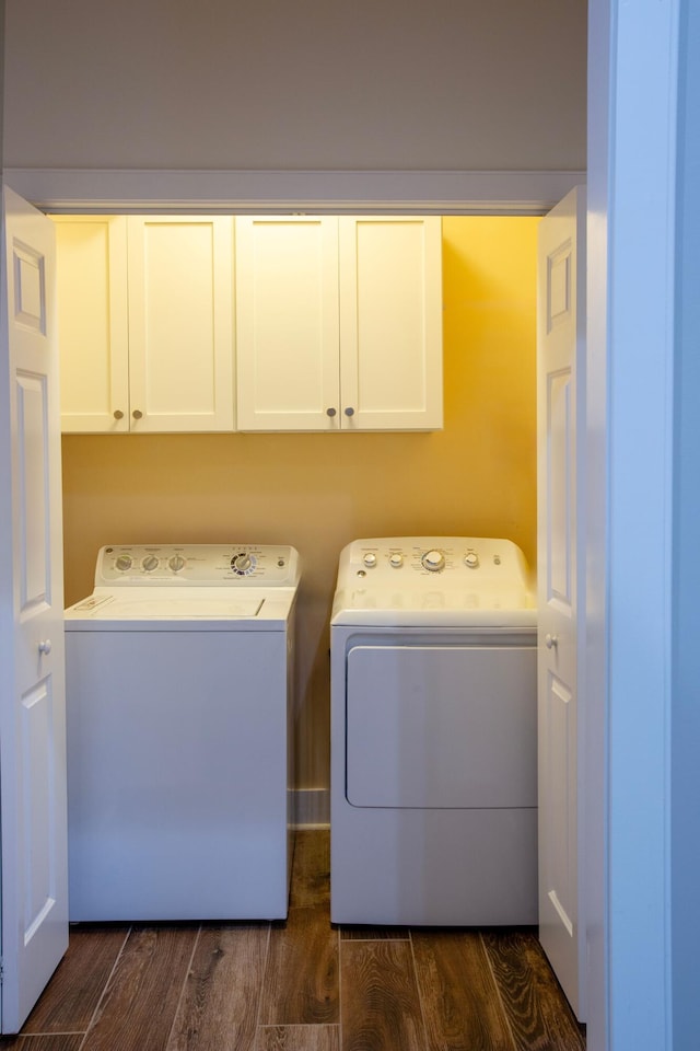 laundry area featuring washing machine and clothes dryer, cabinet space, and dark wood-style flooring