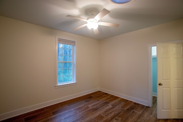 spare room featuring a ceiling fan, dark wood-style floors, and baseboards