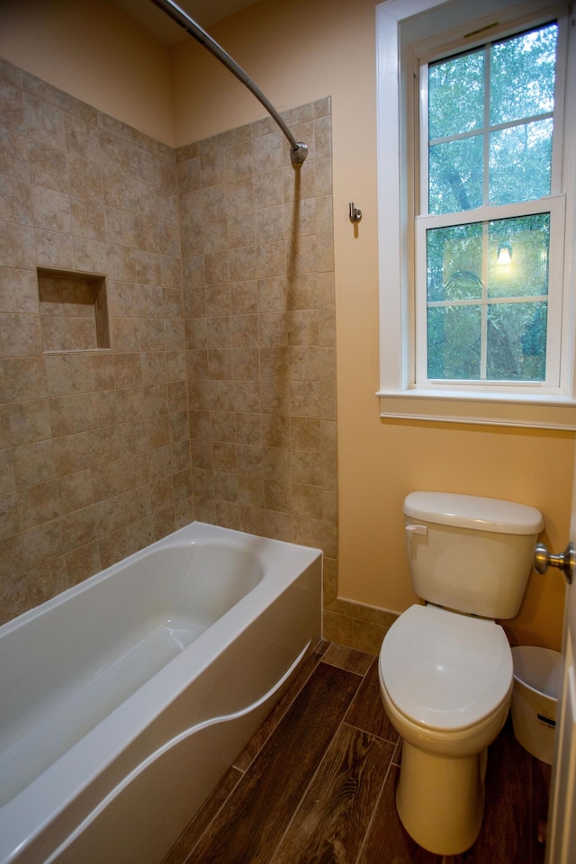 bathroom with toilet, wood finished floors, and shower / washtub combination